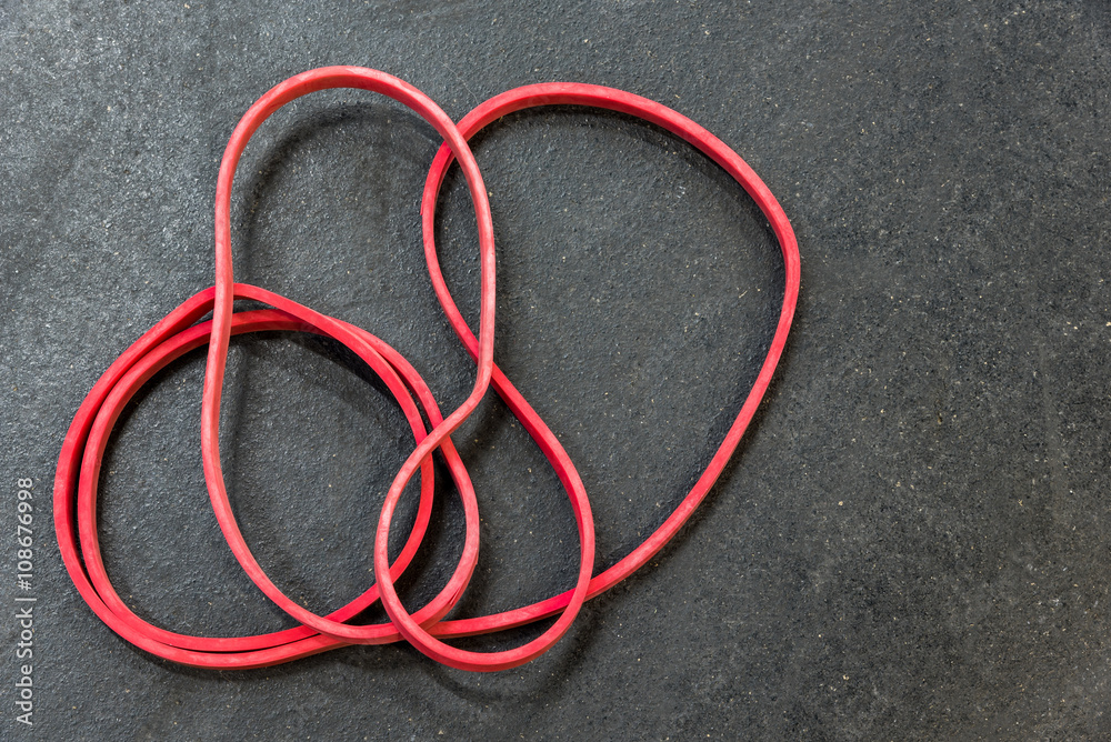 Red resistance band on a black gym floor
Red resistance band on a black gym floor