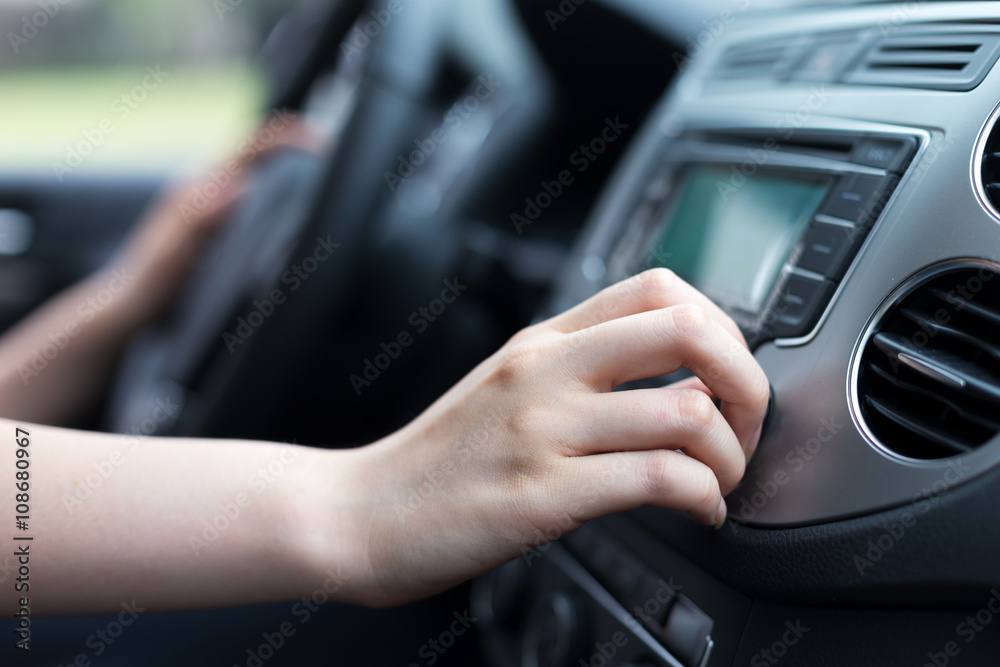woman turning button of radio in car