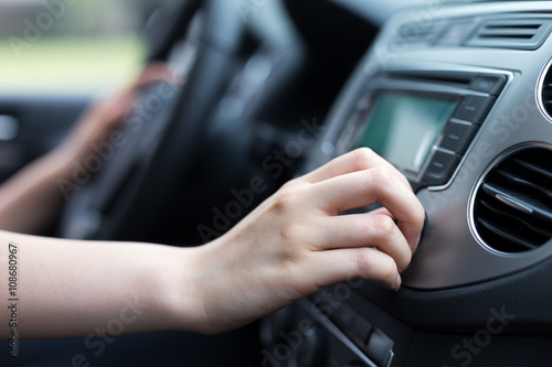 woman turning button of radio in car © zhu difeng
