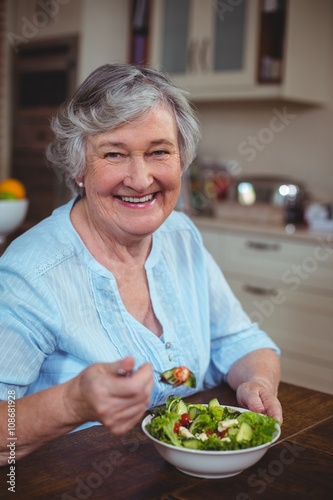 Happy senior woman having vegetable salad 