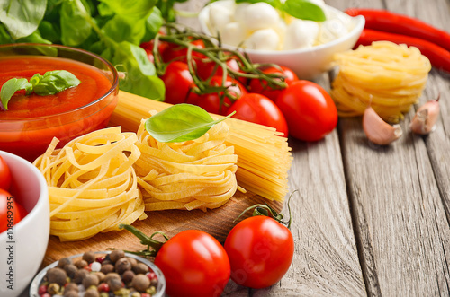 Pasta, vegetables, herbs and spices for Italian food on the rustic wooden table, selective focus, copy space