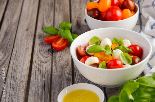 Italian Caprese salad with cherry tomatoes, small mozzarella and fresh basil, selective focus, copy space