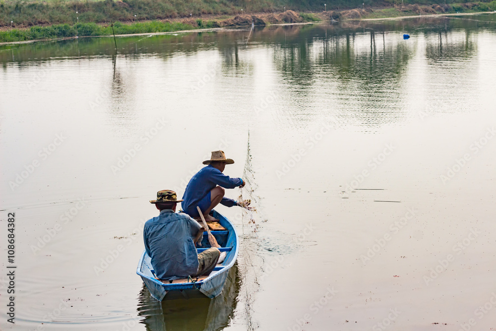 The fisherman in the boat use net to catch fish in the river. The fisherman in the boat use net to catch fish in the river.