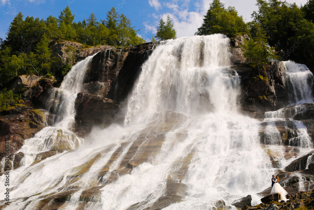 bride and groom posing near the waterfall