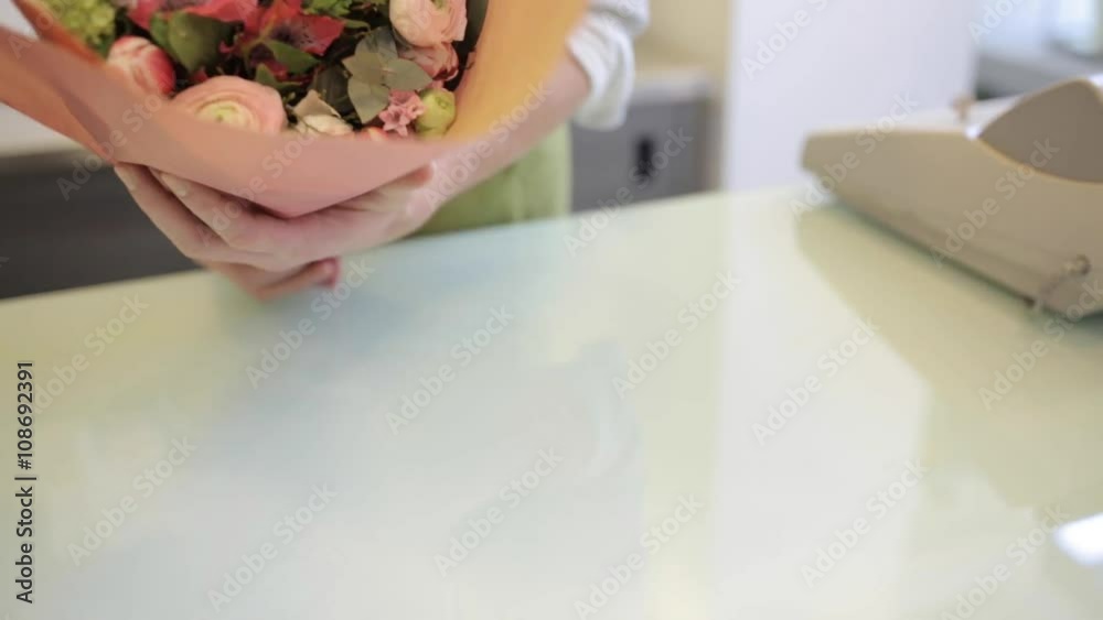 florist wrapping flowers in paper at flower shop