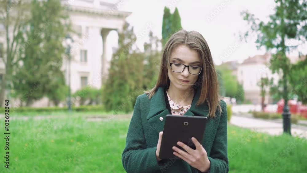 Pretty girl using a tablet on street background 4k Pretty girl using a tablet on street background 4k