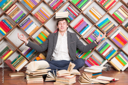 meditating man in the library with books on head