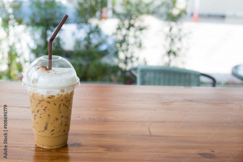 Iced coffee in plastic glass on wooden table. Selective focus. Iced coffee in plastic glass on wooden table. Selective focus.