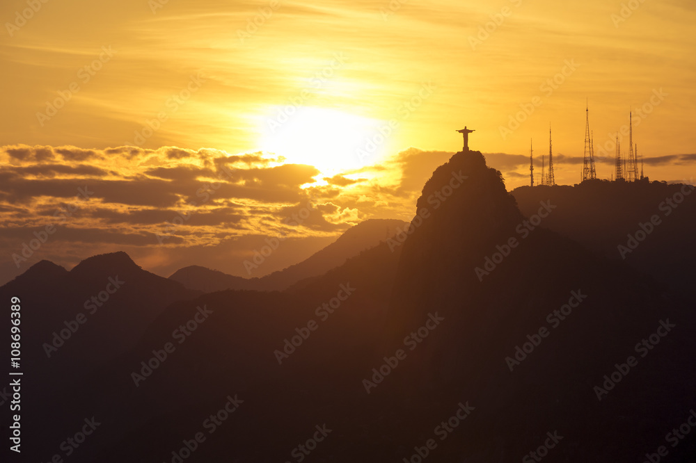 Corcovado mountain Christ the Redeemer standing in golden sunset clouds Rio de Janeiro Brazil