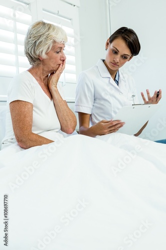 Female doctor with senior woman holding clipboard