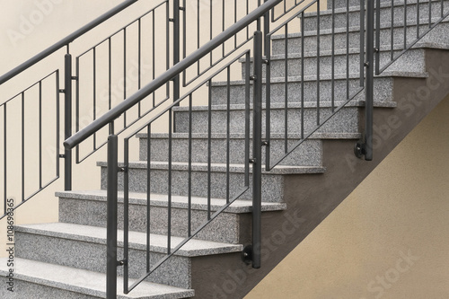Freitragende Außtreppe mit Auflage aus schwarzweißem Granit und Treppengeländer aus Eisen mit Rostschutzfarbe