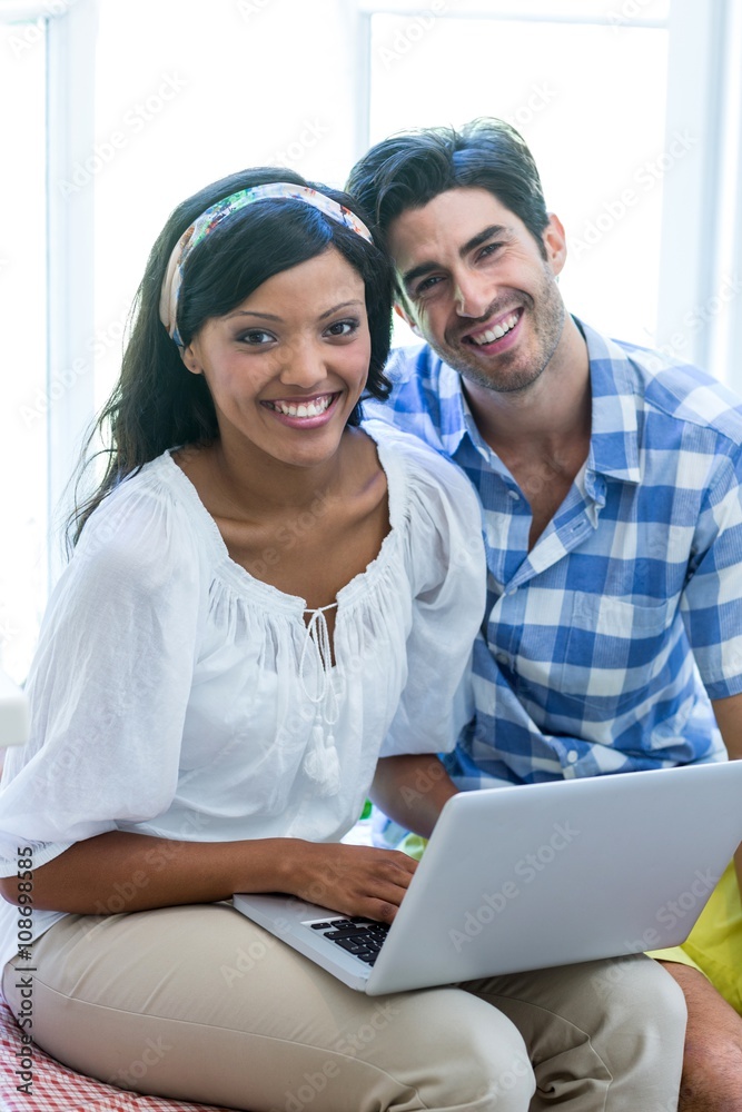 Young couple sitting on bed and using laptop Young couple sitting on bed and using laptop