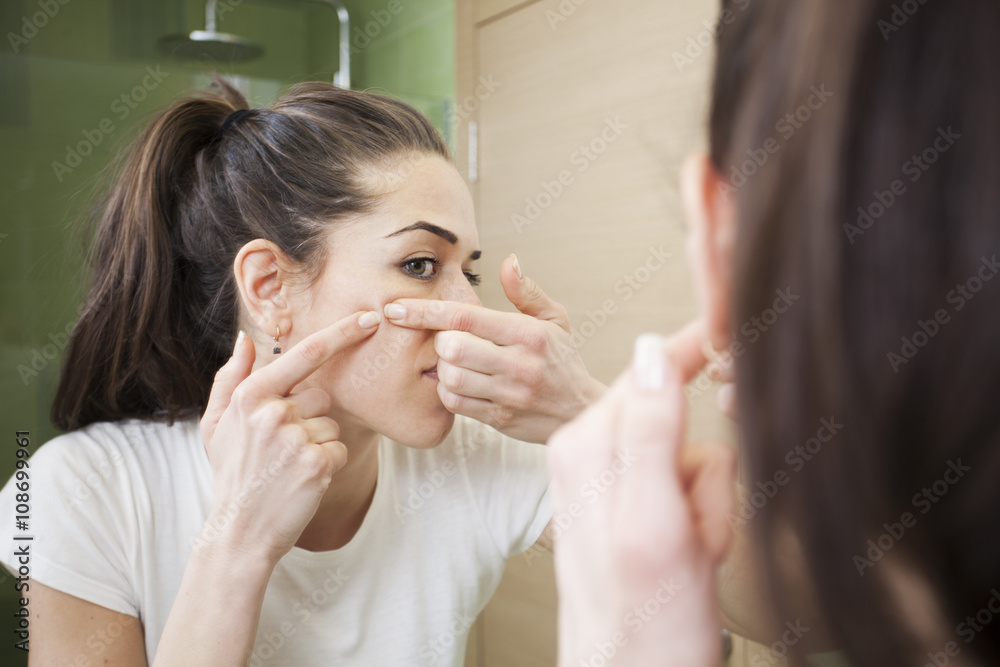 Young woman squeeze her acne in front of the mirror. Skin problems,woman hiving pimple Young woman squeeze her acne in front of the mirror. Skin problems,woman hiving pimple
