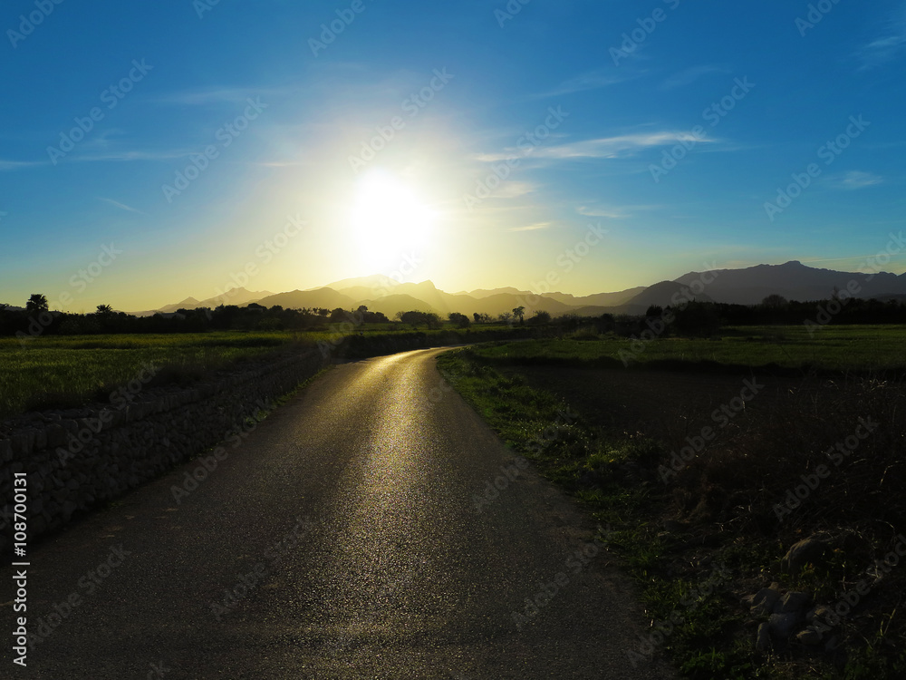 einsame landschaft mit bergen und landstraße im Gegenlicht