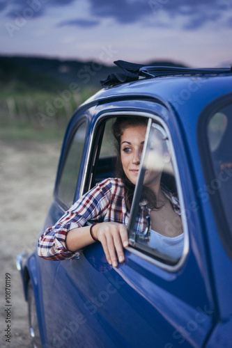 Young couple doing a road trip in Tuscany countryside in a vintage car