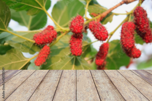 wood table with red mulberries background