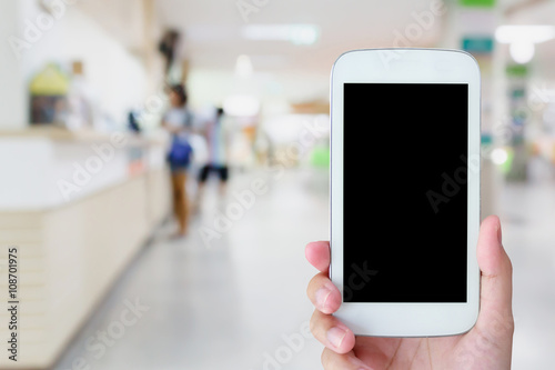 hand hold mobile phone with blurred hospital background