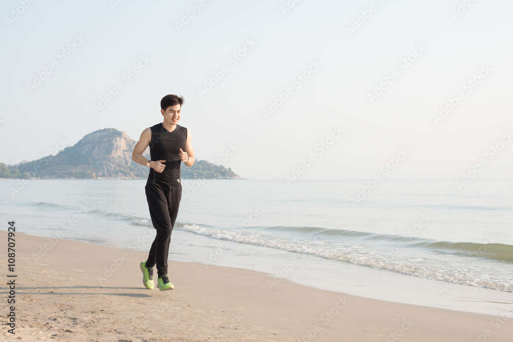 Asian young man running alone at the beach in Morning Asian young man running alone at the beach in Morning