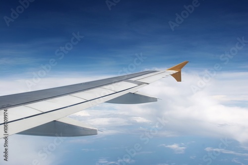 A wing of an aeroplane in the middle of a blue sky
