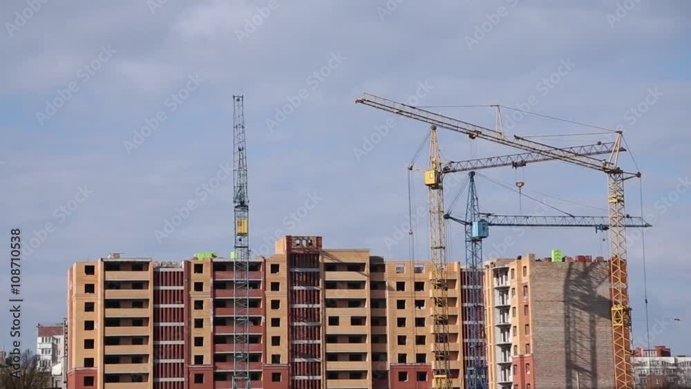 Builder works at against background of the construction site high-rise buildings Builder works at against background of the construction site high-rise buildings
