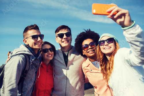 smiling friends taking selfie with smartphone © Syda Productions
