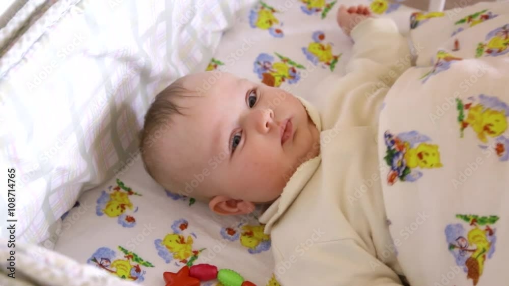 newborn baby girl boy making funny faces smiling and stretching while waking up in own little bed in the bright morning newborn baby girl boy making funny faces smiling and stretching while waking up in own little bed in the bright morning