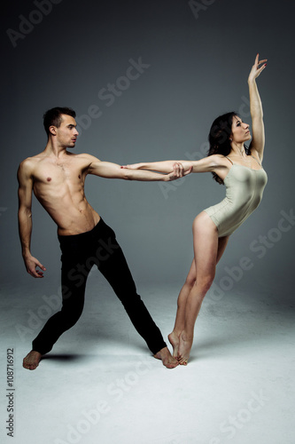 Flexible young modern acrobats couple posing in studio. Fashion portrait of attractive dancing couple. Man and woman. Passion. Love. perfect skin facial and make-up. The guy's pumped abs.