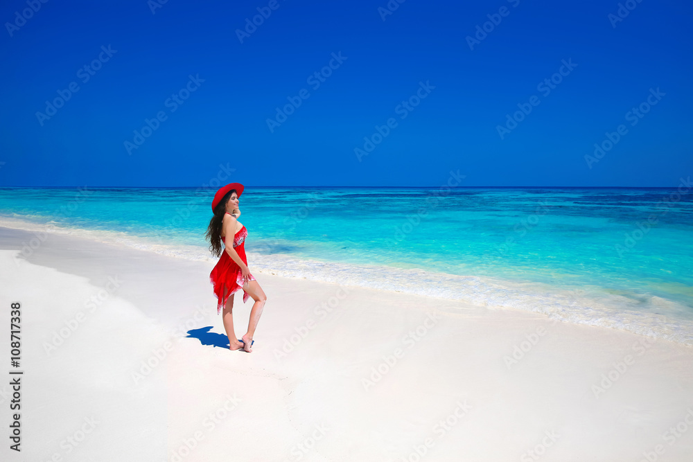 Beautiful woman in hat enjoying summer vacation on exotic beach