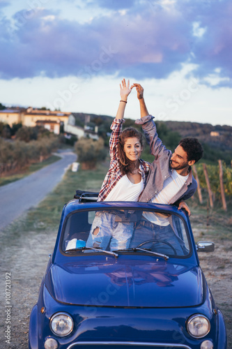 Young couple doing a road trip in Tuscany countryside in a vintage car © juripozzi
