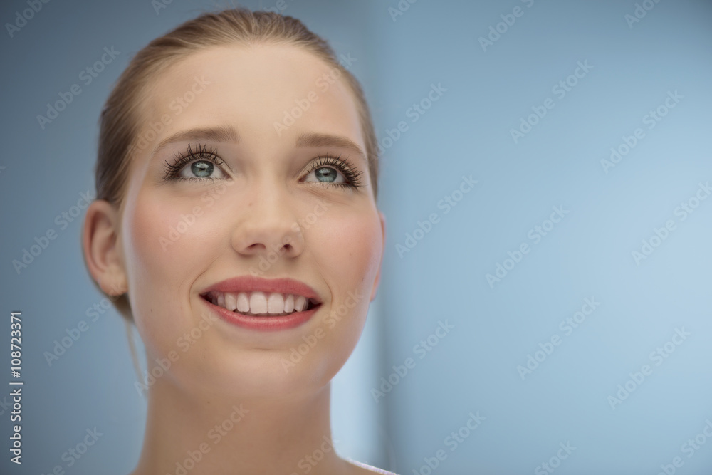 Beautiful girl looking into the air in front of blue background Beautiful girl looking into the air in front of blue background