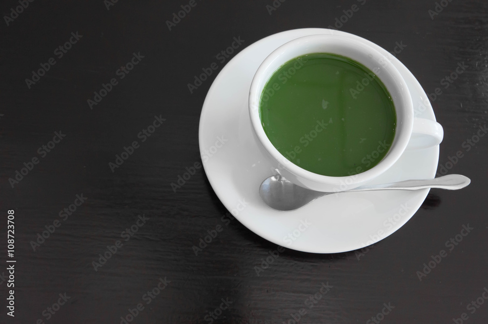 hot milk green tea in white teacup , black wooden background hot milk green tea in white teacup , black wooden background
