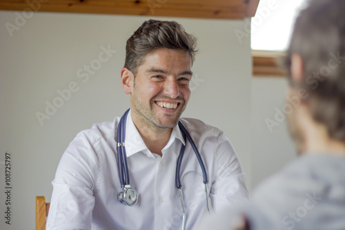 Young doctor with stethoscope and nice smile on his face attends