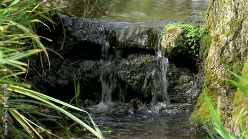 Small waterfall on a narrow flowing stream or babbling brook.