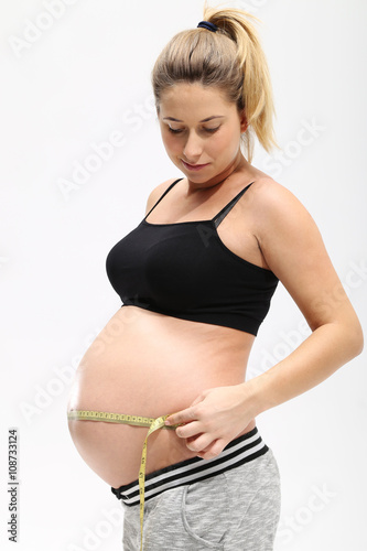 Kobieta w ciąży mierzy brzuch na białym tle