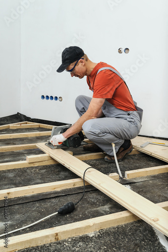 Worker cuts wooden floorboards.