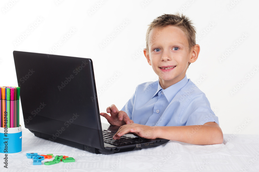 Happy schoolboy is doing homework on laptop Happy schoolboy is doing homework on laptop