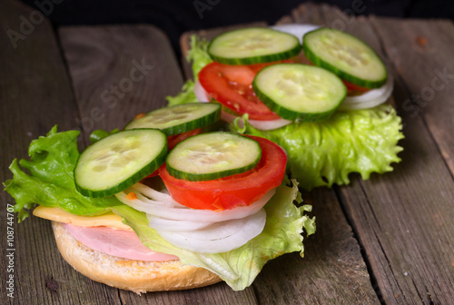 Sandwich with salad and other vegetables on old gray boards