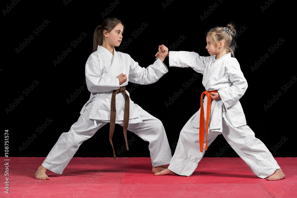 Two girls in kimono are training paired exercises karate