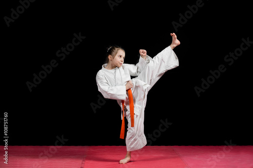 Little girl practice karate isolated on black