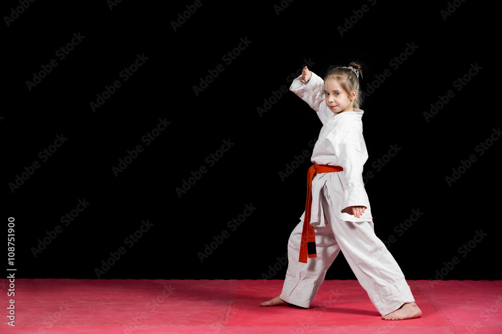 Little girl practice karate isolated on black