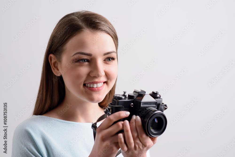 Cheerful smiling girl holding photo camera Cheerful smiling girl holding photo camera