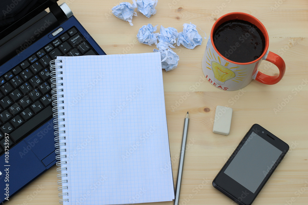 On the desktop - laptop, mobile phone, notebook and pencils. a cup of coffee.view from above On the desktop - laptop, mobile phone, notebook and pencils. a cup of coffee.view from above