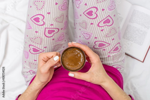 Woman having a cup of coffee in bed