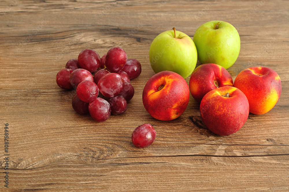 Apples, nectarines and grapes displayed on a wooden background Apples, nectarines and grapes displayed on a wooden background