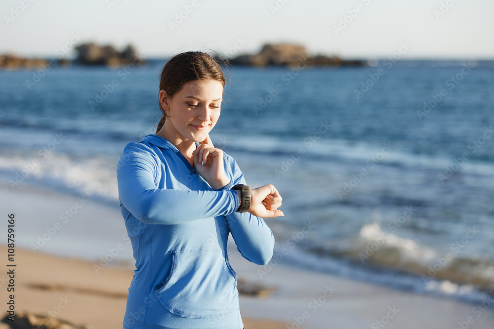 Runner woman with heart rate monitor running on beach Runner woman with heart rate monitor running on beach