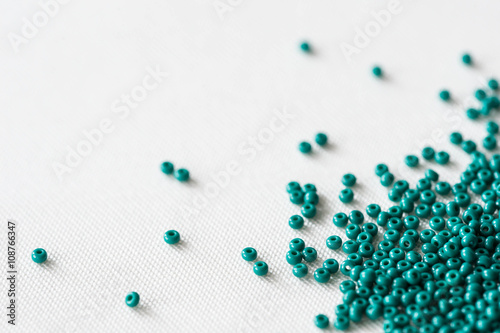 Scattered seed beads of emerald color on the textile background  photo