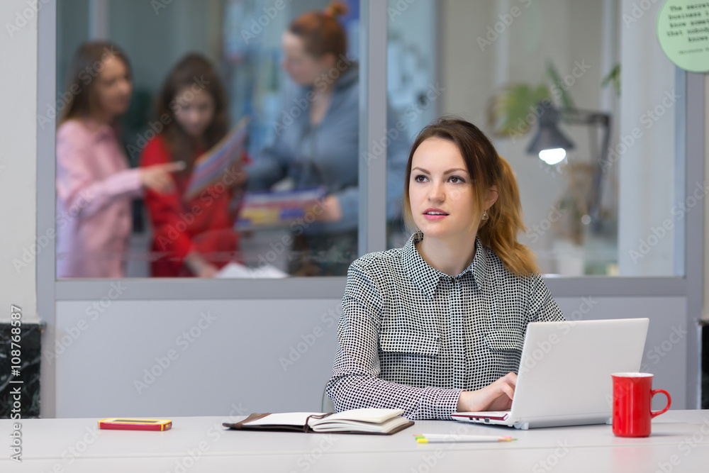 Young female Trainee working on Laptop in Office Interior Young female Trainee working on Laptop in Office Interior