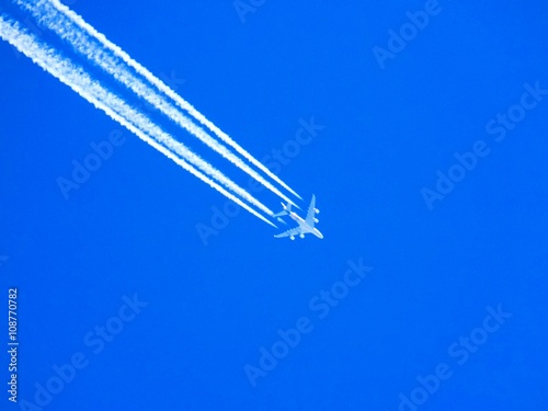 Airplane with chemtrails on blue sky
