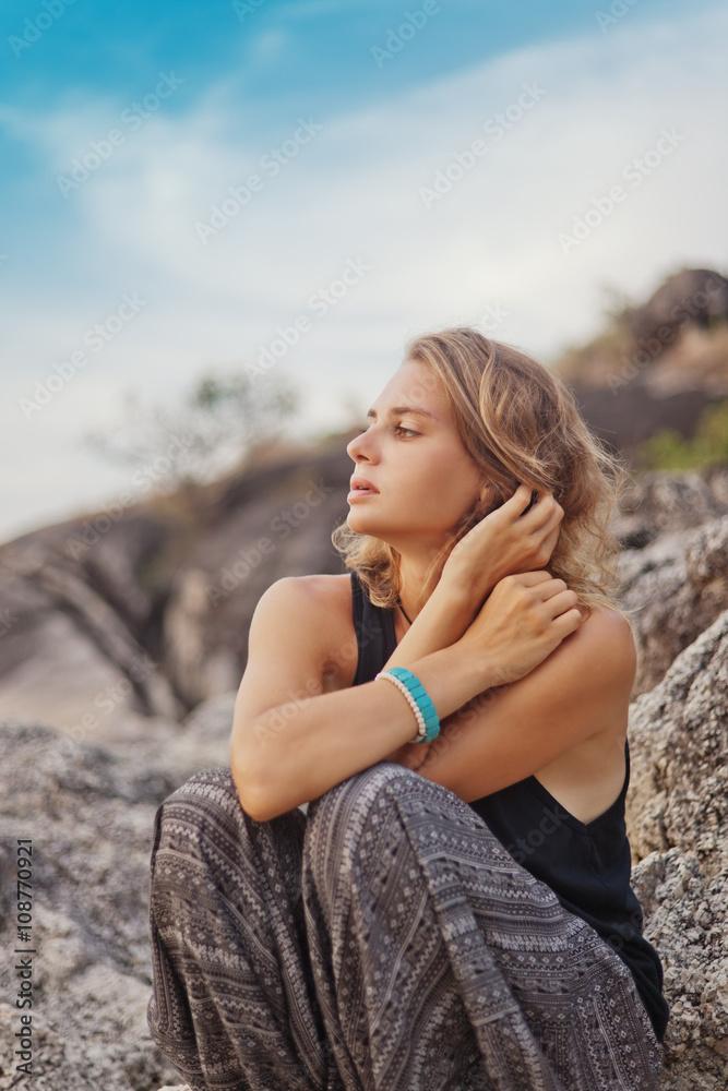Fototapeta premium beautiful young woman sitting on the rocks, outdoor.