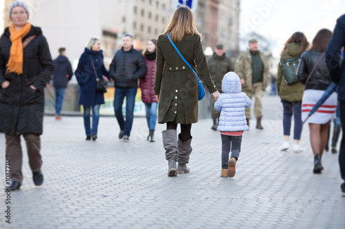 Mother and Daughter walking on City Street among Crowd